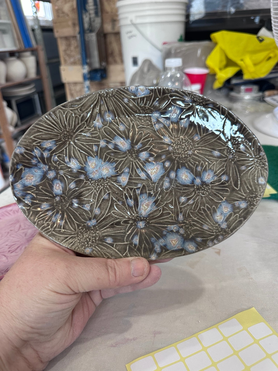 Handmade oval stoneware plate with dark glaze and blue floral texture